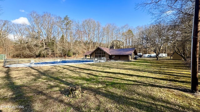 rear view of property featuring a covered pool and a lawn