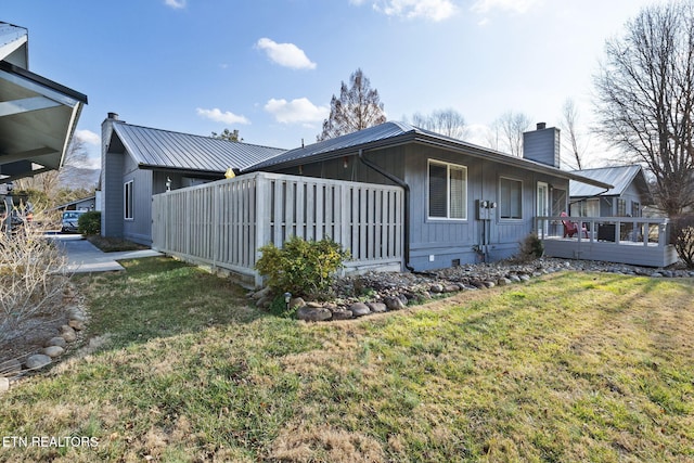 view of side of home featuring a wooden deck and a yard