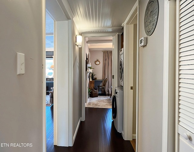 corridor with stacked washer / drying machine and dark hardwood / wood-style flooring