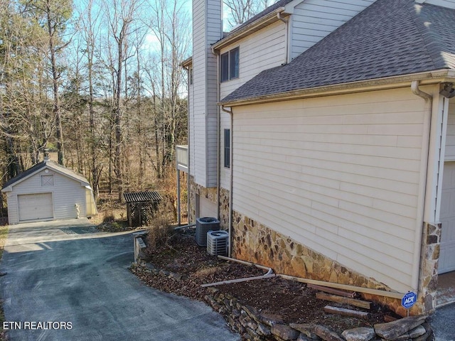 view of property exterior with a garage, an outdoor structure, and central air condition unit