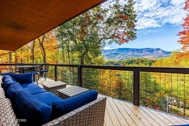 wooden deck with an outdoor living space and a mountain view