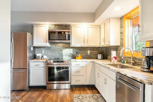 kitchen featuring sink, appliances with stainless steel finishes, white cabinetry, tasteful backsplash, and dark hardwood / wood-style flooring