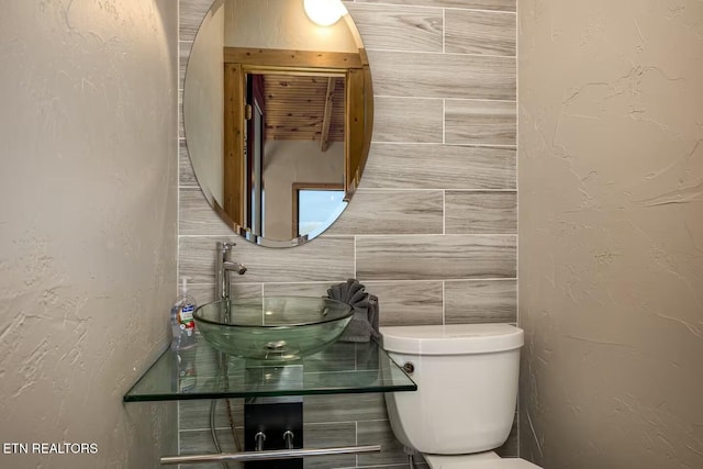 bathroom featuring tile walls, sink, and toilet