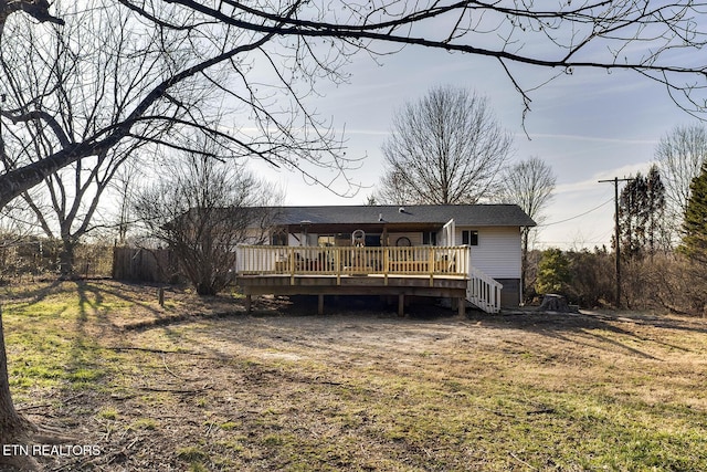 back of property featuring a deck and a lawn