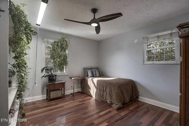 bedroom with ceiling fan, dark hardwood / wood-style floors, and a textured ceiling