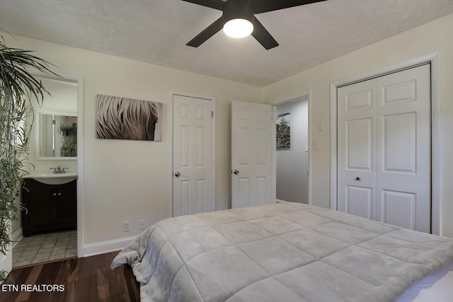 bedroom with sink, ensuite bath, a textured ceiling, hardwood / wood-style flooring, and ceiling fan