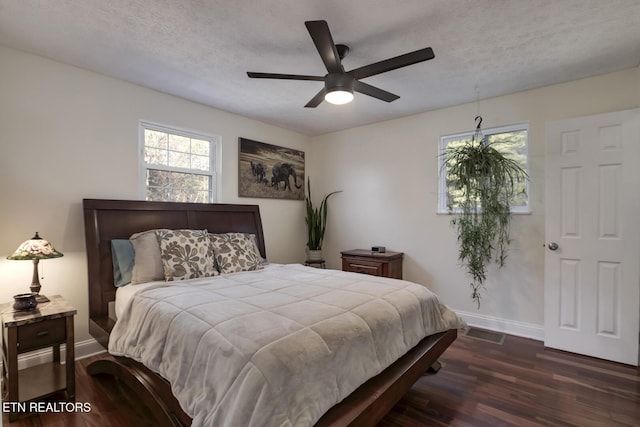 bedroom with ceiling fan, dark hardwood / wood-style floors, and a textured ceiling