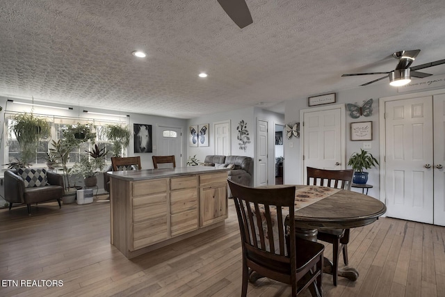 dining space with ceiling fan, a textured ceiling, and light wood-type flooring