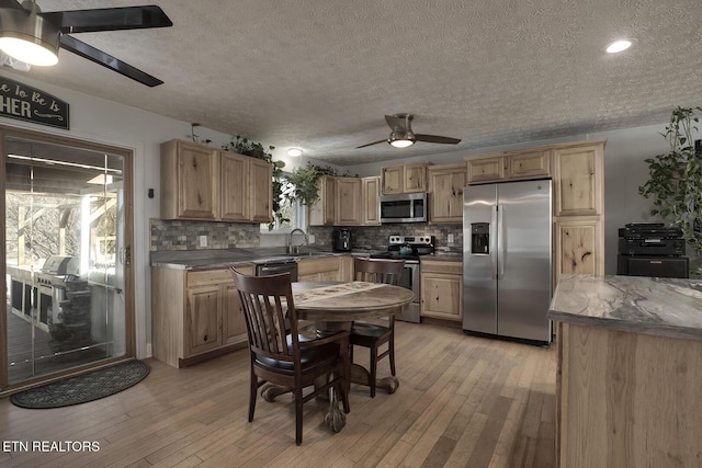 kitchen with tasteful backsplash, sink, ceiling fan, stainless steel appliances, and light hardwood / wood-style flooring