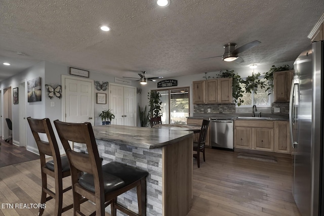 kitchen featuring sink, wood-type flooring, stainless steel appliances, and ceiling fan