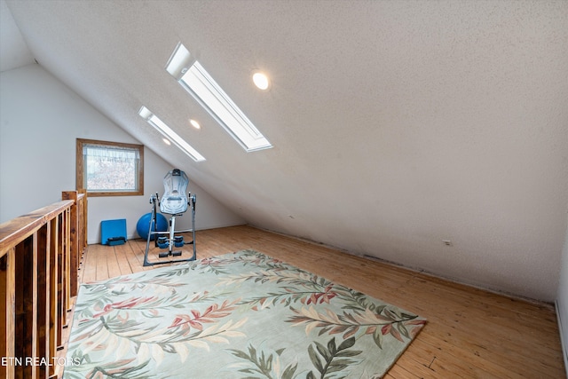 additional living space with light hardwood / wood-style flooring and vaulted ceiling with skylight