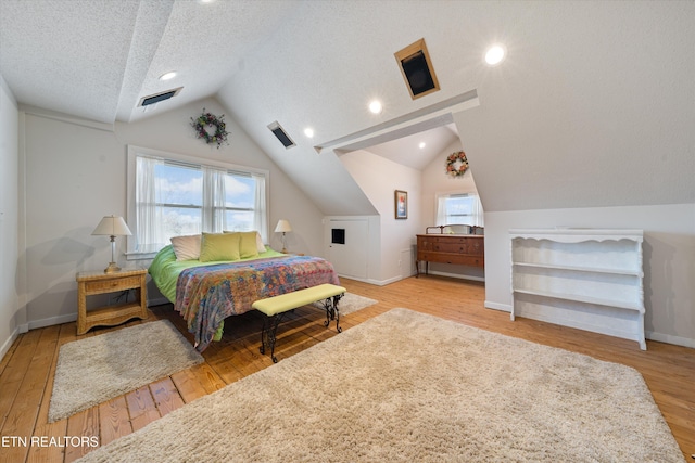 bedroom with multiple windows, lofted ceiling, a textured ceiling, and light wood-type flooring