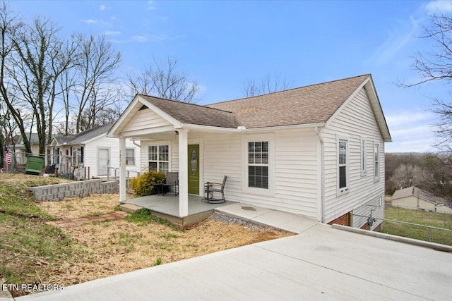 bungalow-style home with roof with shingles and a patio