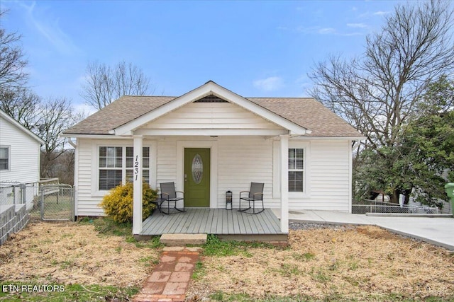 rear view of property featuring a shingled roof and fence