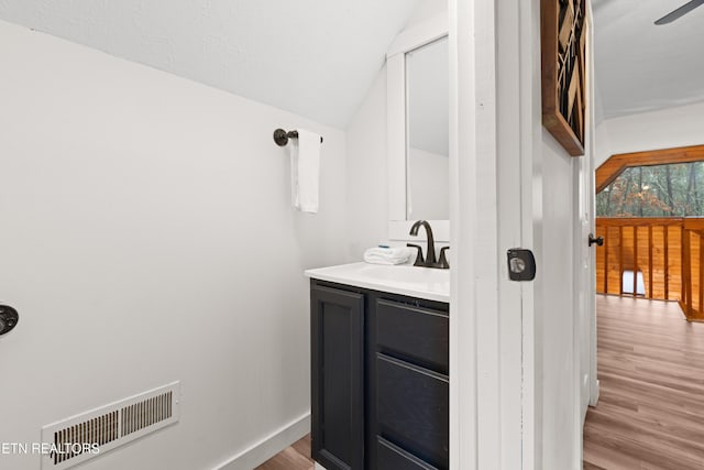 bathroom featuring vanity, hardwood / wood-style floors, and vaulted ceiling