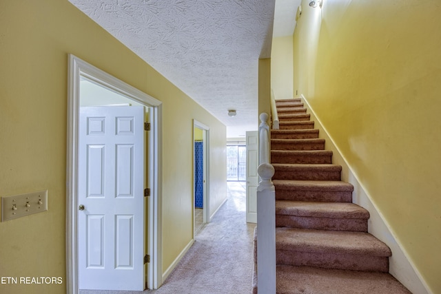 stairway with carpet flooring and a textured ceiling