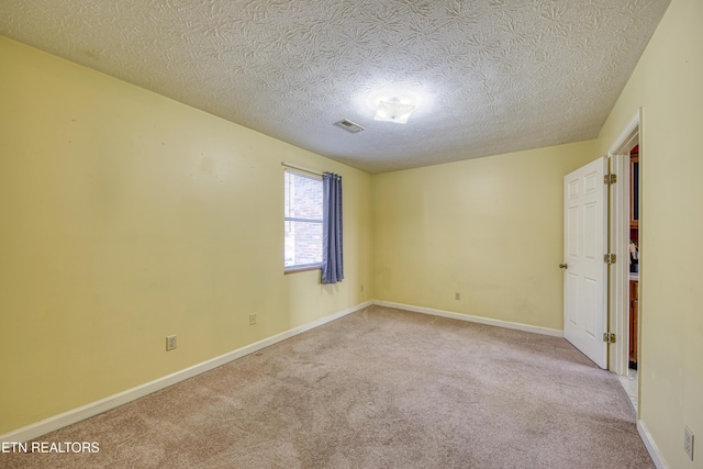 carpeted empty room with a textured ceiling