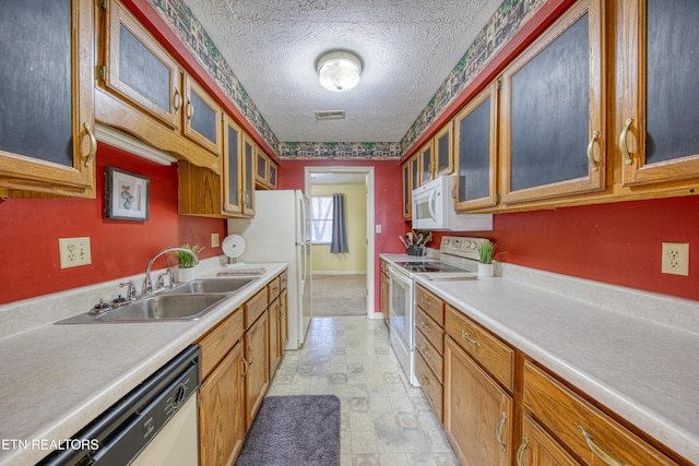 kitchen with sink, white appliances, and a textured ceiling