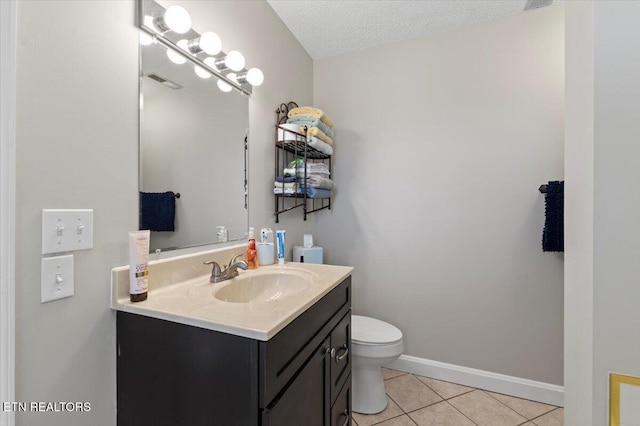 bathroom featuring vanity, toilet, tile patterned flooring, and a textured ceiling