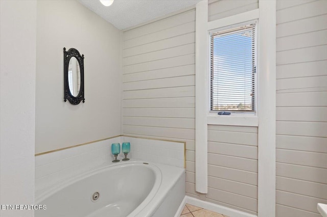 bathroom featuring a bathtub, tile patterned floors, a textured ceiling, and wood walls