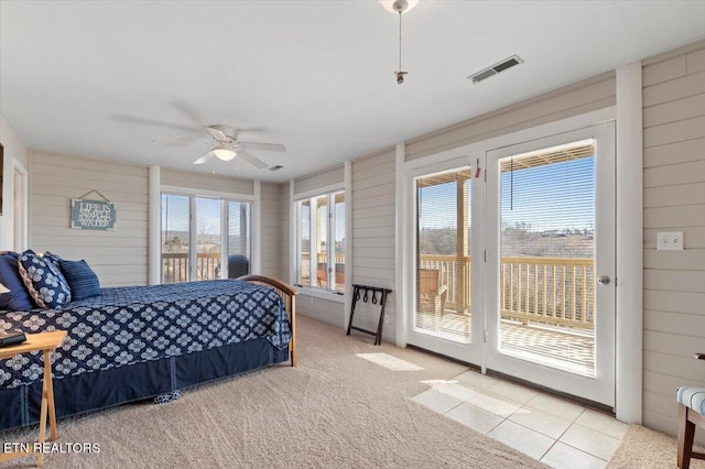 carpeted bedroom with ceiling fan, access to exterior, and wood walls