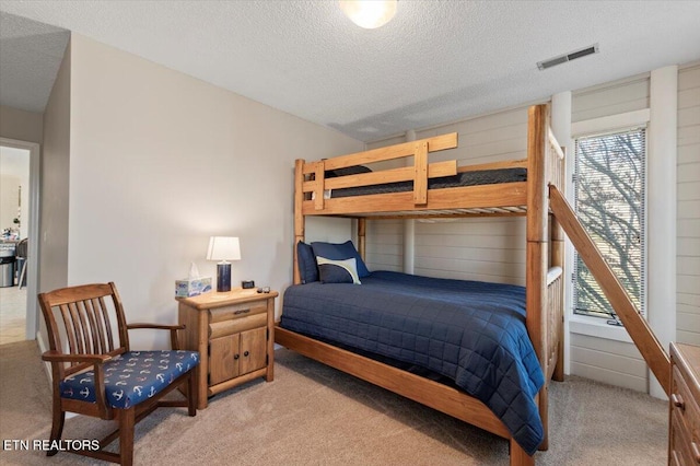 bedroom featuring multiple windows, light carpet, and a textured ceiling