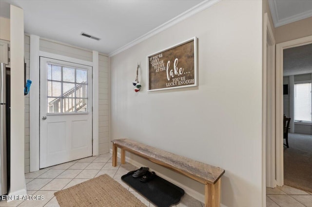 doorway to outside with ornamental molding and light tile patterned flooring