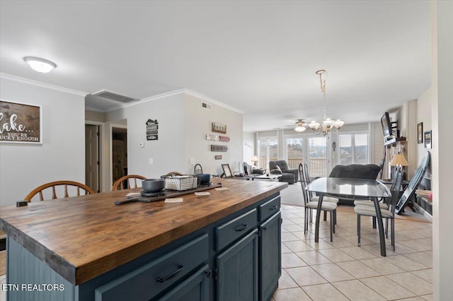 kitchen featuring blue cabinetry, butcher block countertops, decorative light fixtures, light tile patterned floors, and a kitchen island