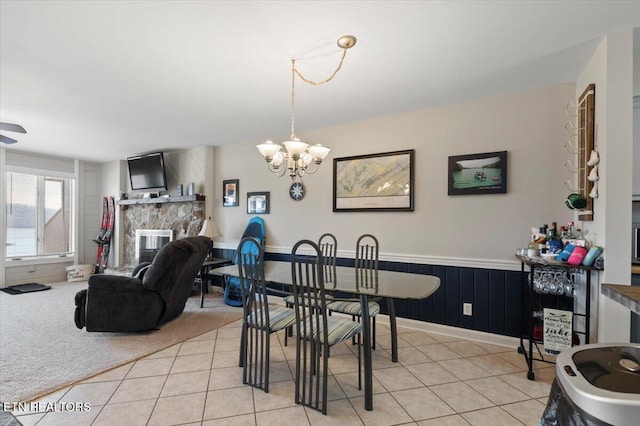 dining space with an inviting chandelier, light tile patterned floors, and a fireplace