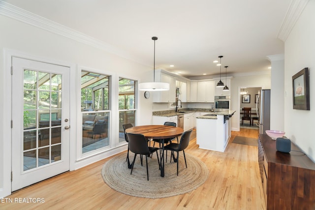 dining area featuring sink, ornamental molding, and light wood-type flooring