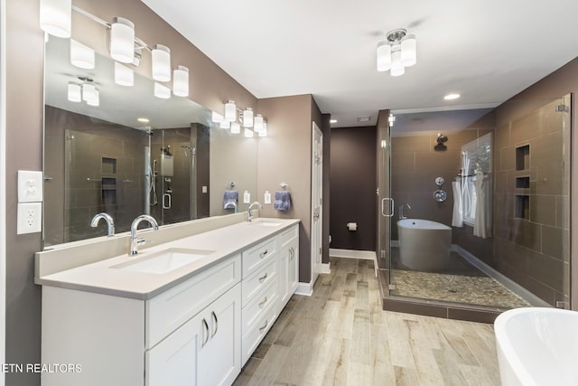 full bathroom featuring independent shower and bath, wood-type flooring, vanity, and toilet