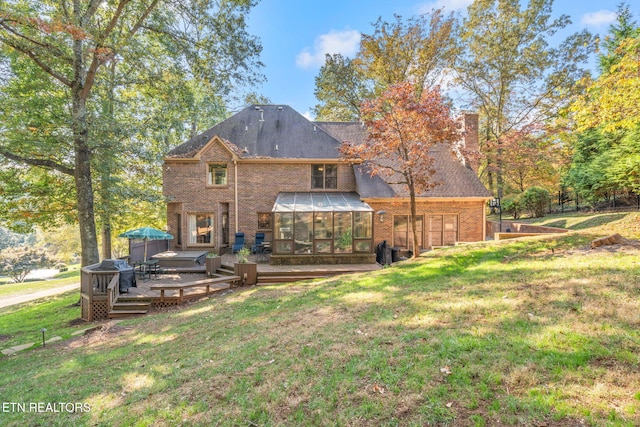 back of property with a sunroom, a deck, and a lawn