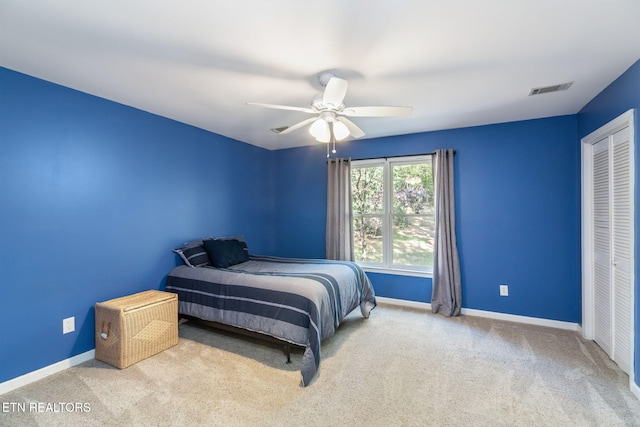 bedroom featuring light carpet, ceiling fan, and a closet