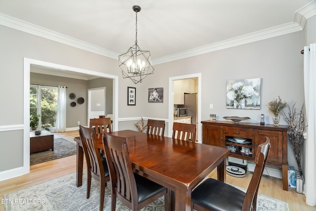 dining room with ornamental molding, a chandelier, and light hardwood / wood-style flooring