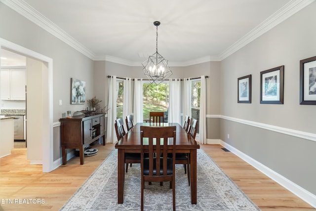 dining area featuring crown molding, a chandelier, and light wood-type flooring