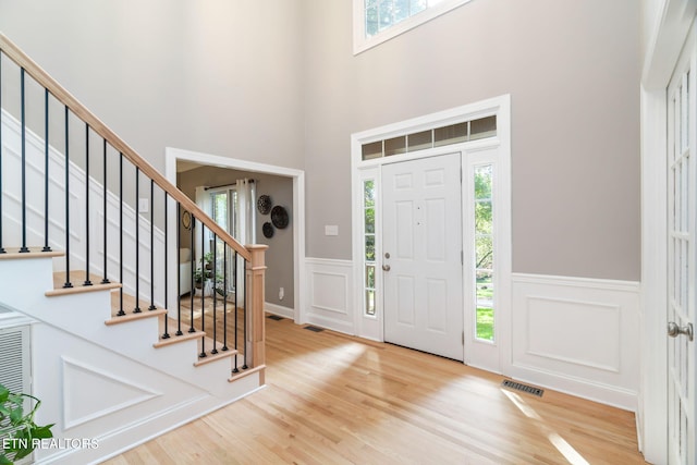 foyer featuring hardwood / wood-style flooring, a towering ceiling, and plenty of natural light