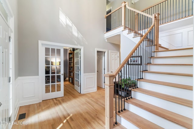 stairway featuring hardwood / wood-style flooring, french doors, and a high ceiling