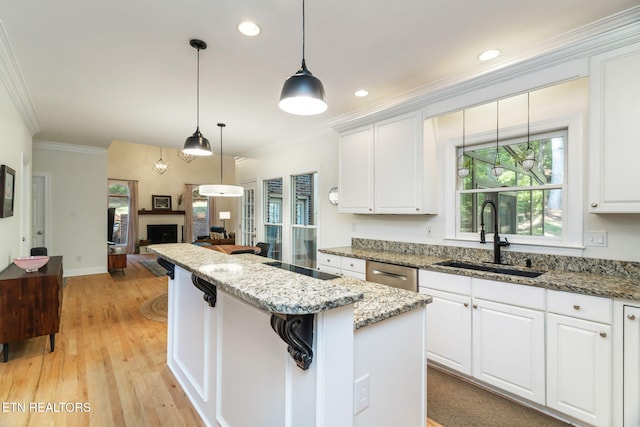 kitchen with sink, hanging light fixtures, ornamental molding, white cabinets, and a kitchen island