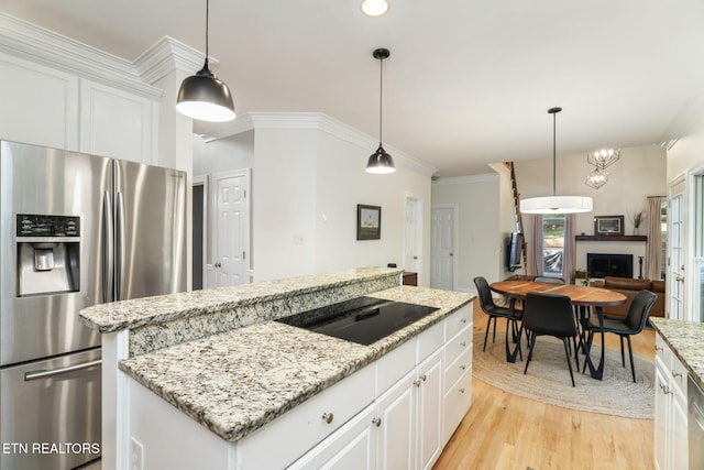 kitchen with stainless steel refrigerator with ice dispenser, white cabinetry, black electric stovetop, and decorative light fixtures