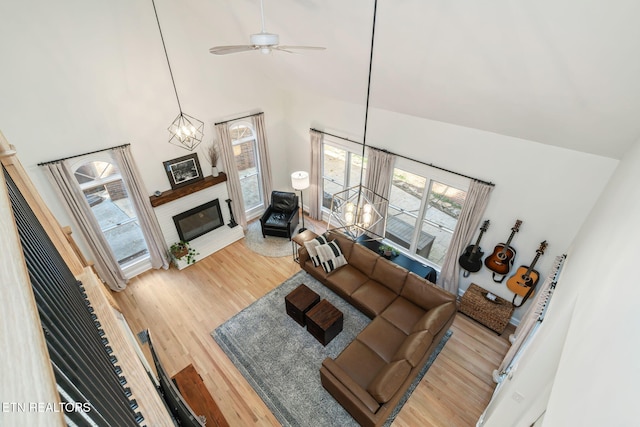 living room featuring wood-type flooring, a towering ceiling, and ceiling fan with notable chandelier