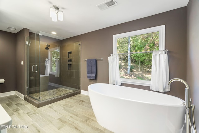 bathroom with hardwood / wood-style flooring and shower with separate bathtub