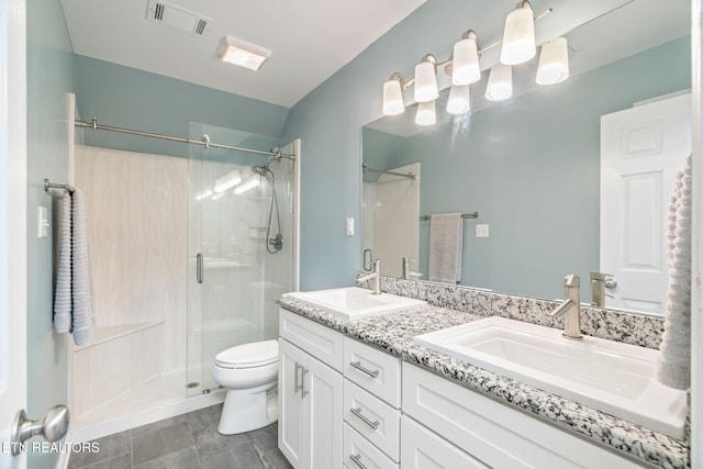 bathroom featuring a shower with door, vanity, and toilet