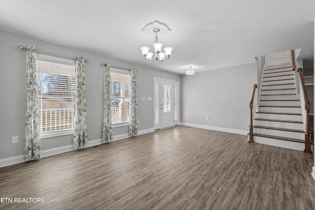 unfurnished living room with an inviting chandelier and dark wood-type flooring