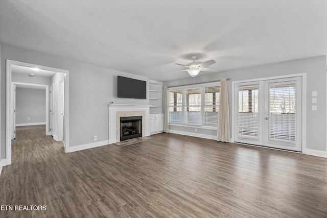 unfurnished living room featuring dark wood-type flooring, french doors, a textured ceiling, a tile fireplace, and ceiling fan