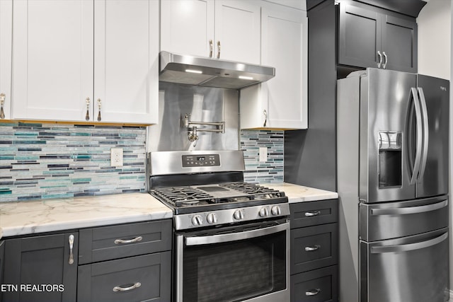 kitchen with stainless steel appliances, light stone countertops, decorative backsplash, and white cabinets