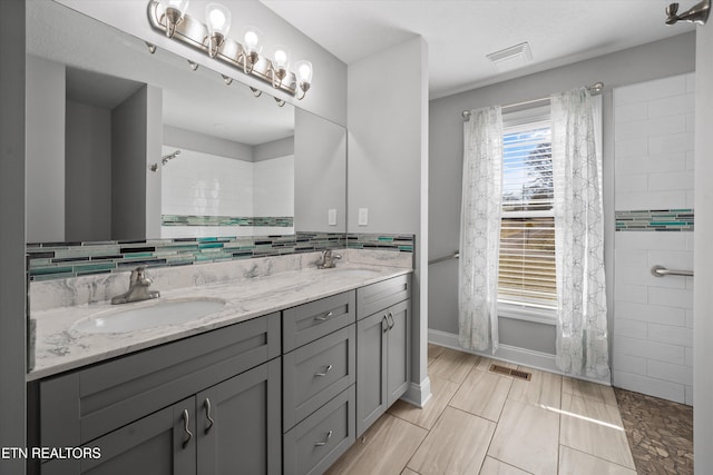 bathroom featuring vanity, tiled shower, and decorative backsplash