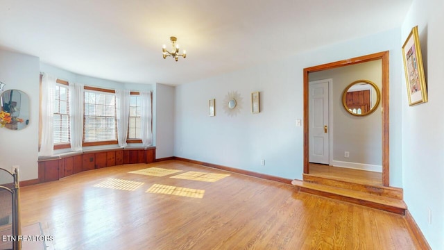 spare room featuring an inviting chandelier and light hardwood / wood-style floors