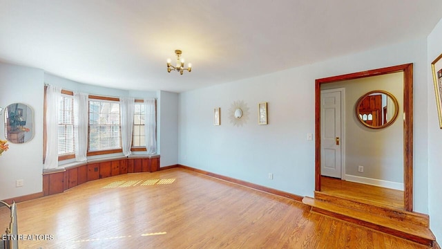 spare room with light hardwood / wood-style flooring and a notable chandelier