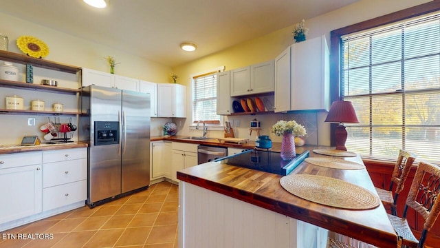 kitchen featuring stainless steel appliances, butcher block counters, light tile patterned floors, and white cabinets