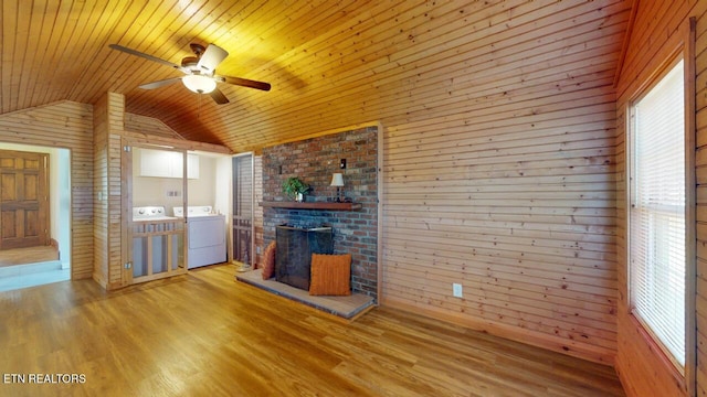 unfurnished living room featuring lofted ceiling, wood ceiling, light hardwood / wood-style floors, washer and dryer, and a brick fireplace